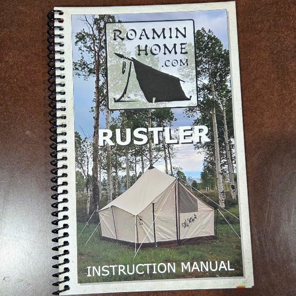 A spiral-bound instruction manual for the Roamin Home.com Rustler tent, placed on a brown wooden table.